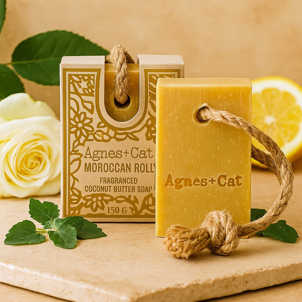 Agnes + Cat Moroccan Roll soap with packaging on a wooden surface with flowers and leaves.