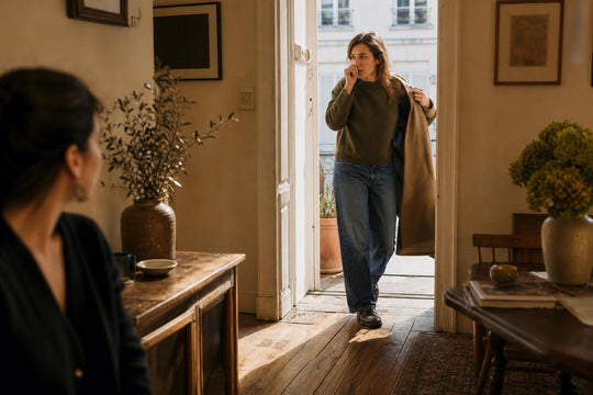 A woman stepping into a room from outdoors, pausing at the doorway
