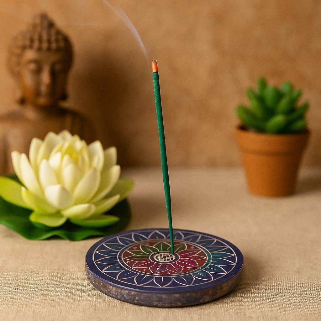 Incense stick on a decorative holder with a Buddha statue and lotus flower in the background.