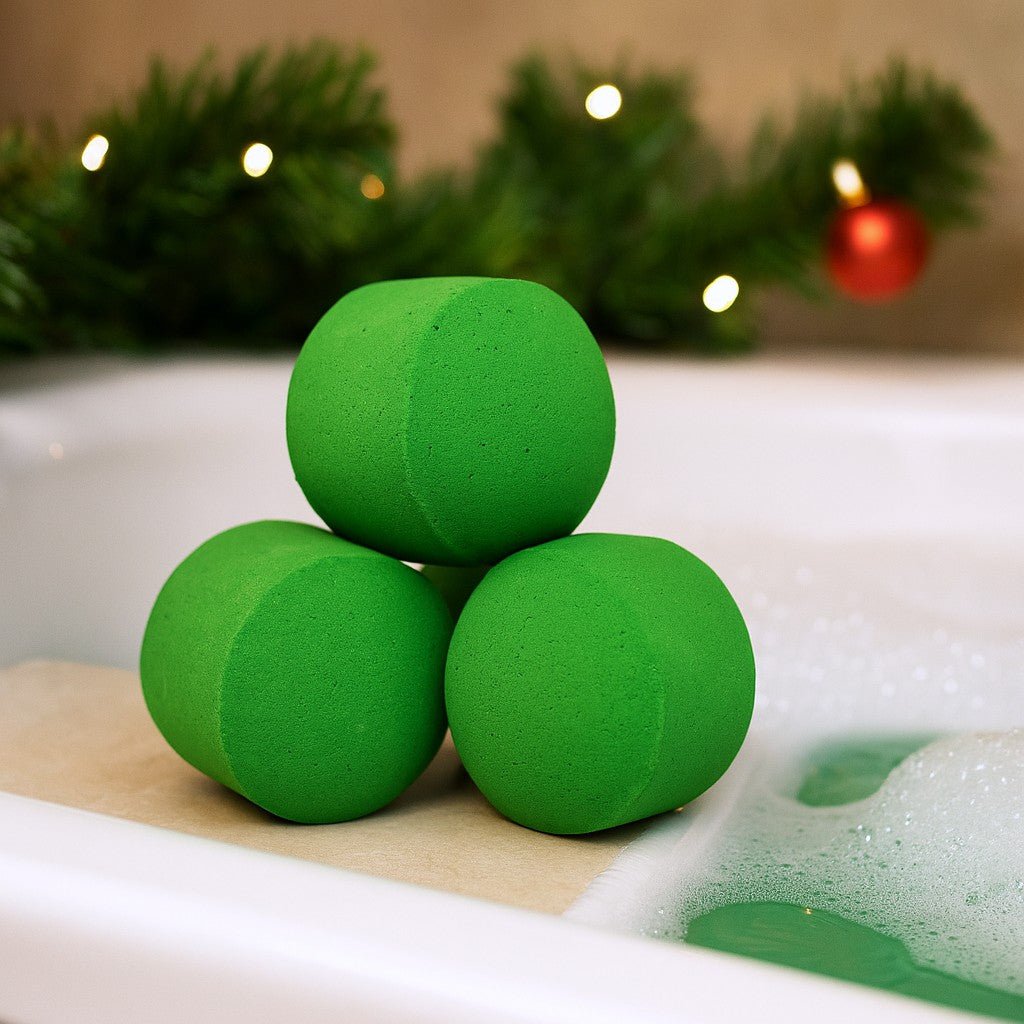 Three green bath bombs on a bathtub with Christmas decorations in the background