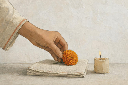 Een hand die een enkele goudsbloem op een opgevouwen altaardoek legt naast een brandende kaars in het rustige ochtendlicht