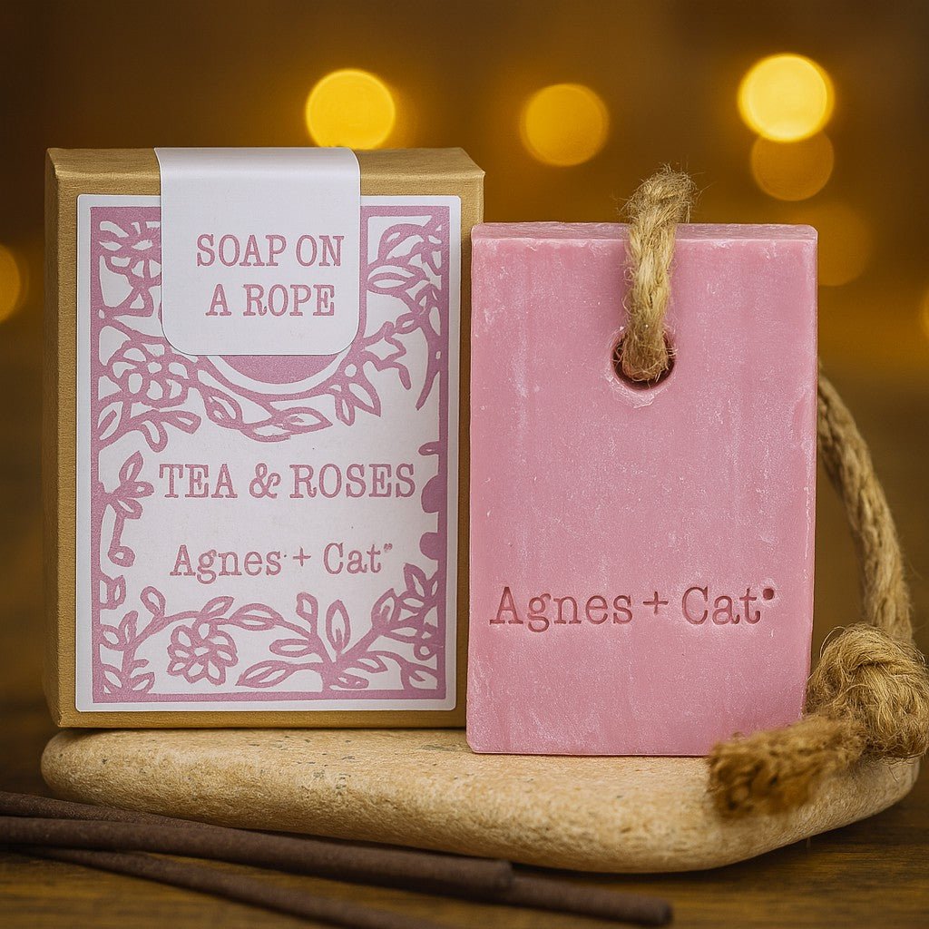 Pink soap on a rope with packaging labeled 'Agnes + Cat' against a warm, blurred background.