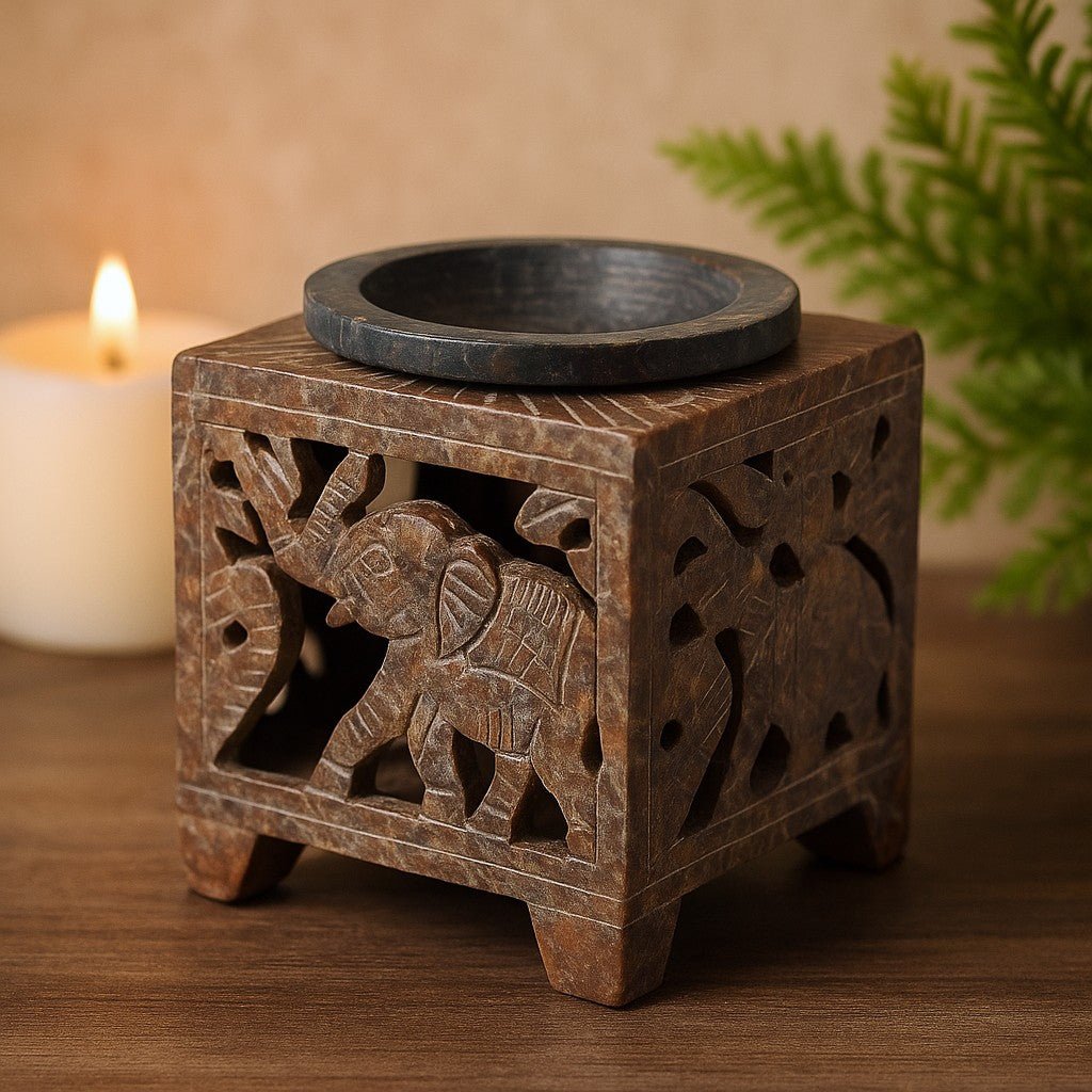 Wooden oil burner with elephant design on a wooden surface, candle in the background