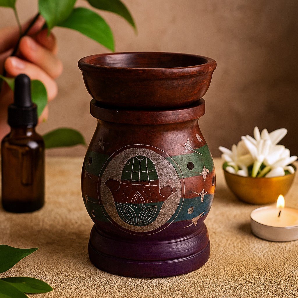 Decorative oil burner with hamsa design on a table with plants and a candle.
