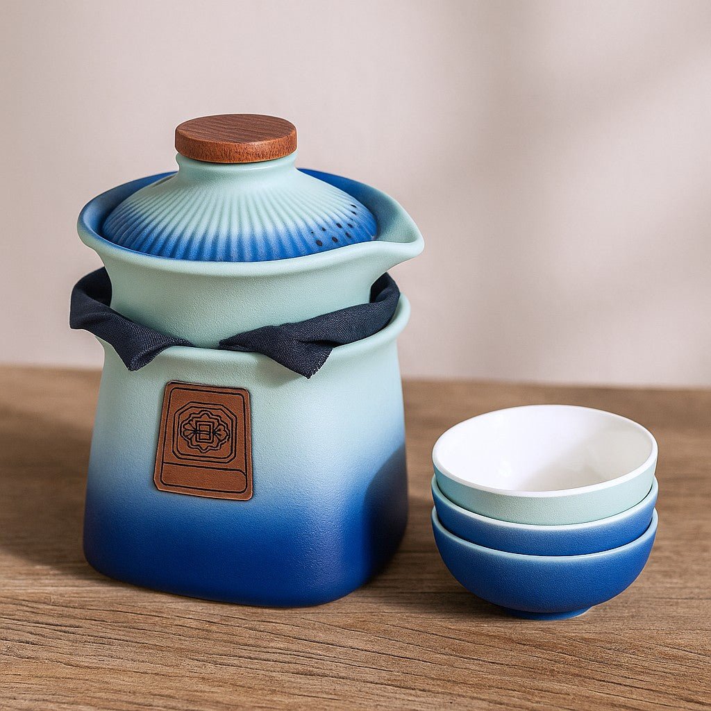 Ceramic teapot with gradient blue design and wooden lid, accompanied by matching bowls on a wooden surface.