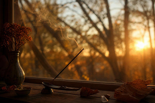 Incense stick burning on a windowsill at dusk in autumn