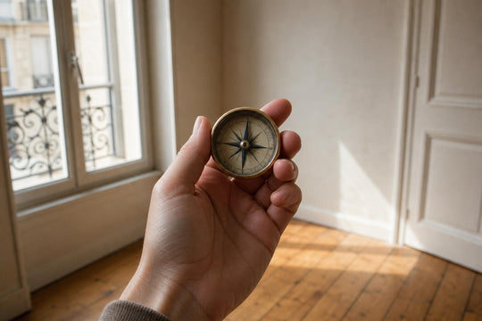 A hand holding a compass to check a room's direction before arranging furniture
