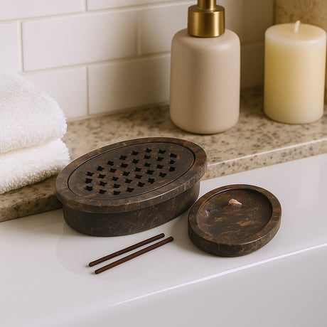 Wooden incense burner with two sticks on a bathroom counter, next to a soap dispenser and candle.