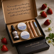 Gift set with mindfulness theme, including a bottle and containers, on a marble surface with strawberries and flowers.