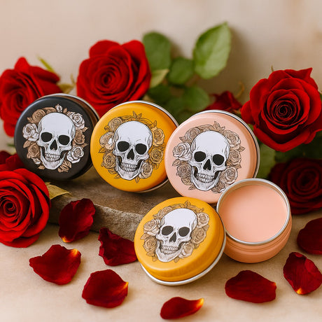 Skull-themed cosmetic containers with decorative designs on lids surrounded by red roses and petals.