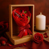 Bouquet of red roses in a box with a lit candle on a brown background