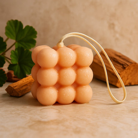 Cylindrical sponge with a string on a wooden surface with a plant and wood piece in the background