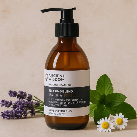 Brown bottle of massage and bath oil with a label, surrounded by lavender flowers and green leaves on a beige background.