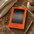 A5 Intention Note Book - LCD Wipe Screen - Orange Leather Effect - 80 Leafs — styled in a warm, naturally lit interior