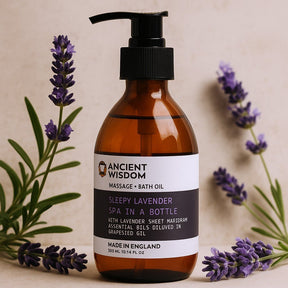 Brown bottle of Ancient Wisdom Sleepy Lavender Massage & Bath Oil with lavender flowers on a beige background