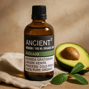 Bottle of Ancient Wisdom avocado oil with an avocado half on a wooden surface