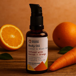Body oil bottle with oranges and a carrot on a wooden surface