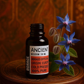 Bottle of 'Ancient Wisdom' borage oil with borage flowers on a wooden surface.