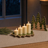 Four Sundays: A modern Advent wreath without the fir: four ivory pillar candles of graduated heights in a green-enamel tree tray, with three carved mango-wood evergreens