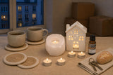 The First Evening Here: A housewarming gift: a white salt tealight holder, a little ceramic house oil burner with cedarwood oil, vanilla tealights and four jute coasters