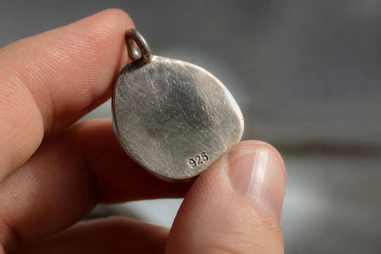Macro close-up of a hallmark stamp on the back of a silver pendant