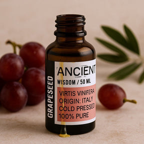 Bottle of Ancient Wisdom grapeseed oil with grapes and an olive leaf on a beige background
