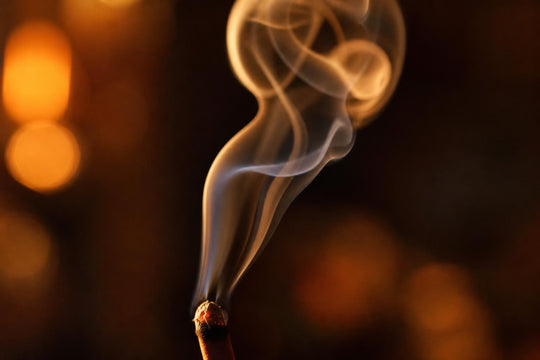 Macro close-up of incense smoke curling upward in warm side light