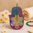 Decorative incense holder with colorful patterns on a beige background with flowers and a towel.
