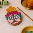Decorative coaster with tree design on a table with a cup and saucer in the background