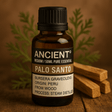Amber glass bottle of 50ml Palo Santo essential oil with wooden sticks and green leaves background