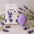 Konjac sponge with lavender packaging and lavender flowers on a light background