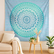 Mandala tapestry on a wall in a living room with a couch and plants.