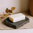 Bar of soap on a dark stone surface with a beige background