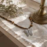 Nymph Tiger's Eye Gemstone Necklace with Real Leaf Butterfly Pendant — styled in a warm, naturally lit interior