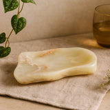 Decorative stone on a textured surface with a plant and glass in the background