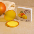 Yellow paper soap with packaging labeled 'Mango' on a beige surface.