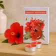 Hibiscus and White Sage scented candles with packaging on a wooden surface