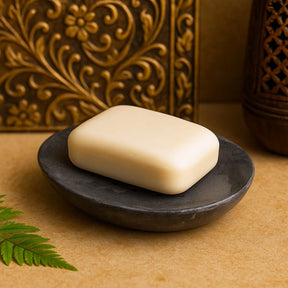 Bar of soap on a dark stone soap dish with decorative background