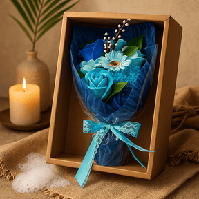Bouquet of blue roses and flowers in a brown box on a textured surface with a candle and vase in the background.