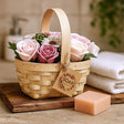 Woven basket with flowers and a bar of soap on a wooden surface