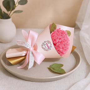 Pink flower bouquet with a bow on a beige plate