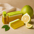 Three bars of green and yellow soap with a lemon and lemon leaves on a beige background