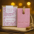 Pink soap on a rope with packaging labeled 'Agnes + Cat' against a warm, blurred background.