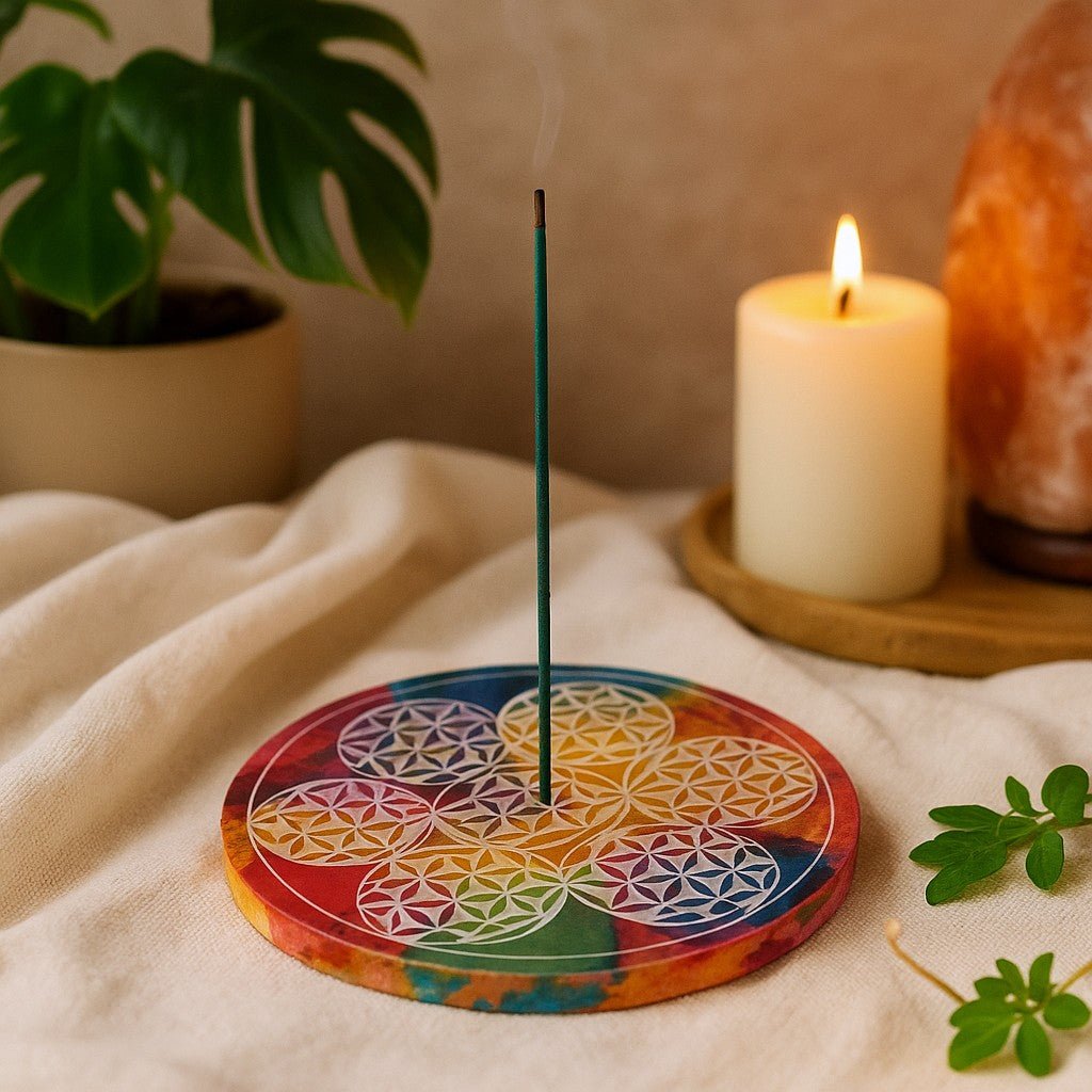 Colorful circular incense holder with a lit candle and plant in the background