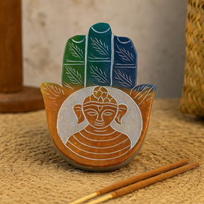 Decorative item with Buddha face and leaves on a textured surface