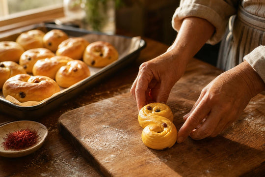 Hands shaping a saffron bun into its traditional S curl on a wooden kitchen counter