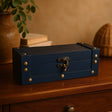 Blue jewelry box with brass accents on a wooden surface with a warm background