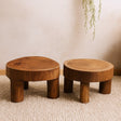 Two wooden stools on a textured floor with a neutral wall background