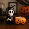 Halloween-themed decoration with a grim reaper figurine and jack-o'-lantern candle holder.