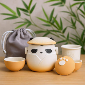Cute panda-shaped ceramic tea set with a gray drawstring bag on a wooden surface.